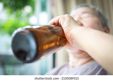 Blur focus,Elderly people with alcoholic drink,drunken,asian senior woman drinking beer from bottle,suffering from alcoholism,health problem,liver disease,alcohol dependence syndrome,alcohol addiction