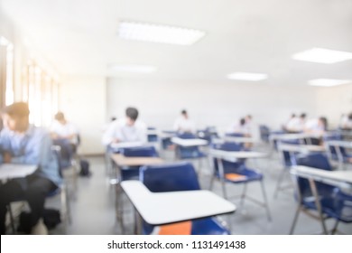 Blur Focus.front View Abstract Background Of Examination Room With College Students Inside. University Student In Uniform Sitting On Lecture Chair Taking Final Exam Or Study At Classroom In School.