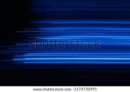 Blur glowing lines. Futuristic neon light. Cyber laser illumination. Defocused fluorescent navy blue color rays flare motion on dark black presentation abstract background.