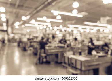 Blur image cashier with line of people at check-out counter. Customers paying with credit card to store clerks, employee bags groceries. Cashier register, checkout payment terminal. Vintage filter.
