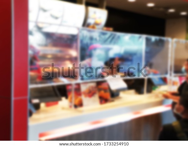 Blur image for clear plastic sheet scene in\
counter fried chicken shop business Prevents the spread of saliva\
spray virus infection of sellers waiting for buyers to order food\
in the close distance.