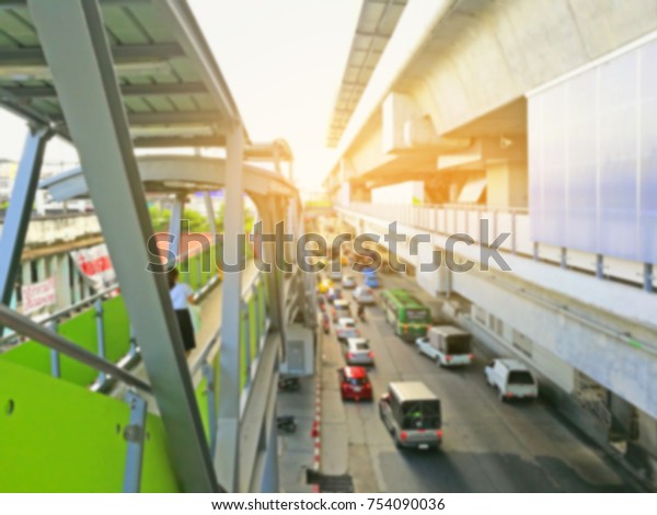 Blur of image of  electric train station and\
traffic car in town with\
sunshine.