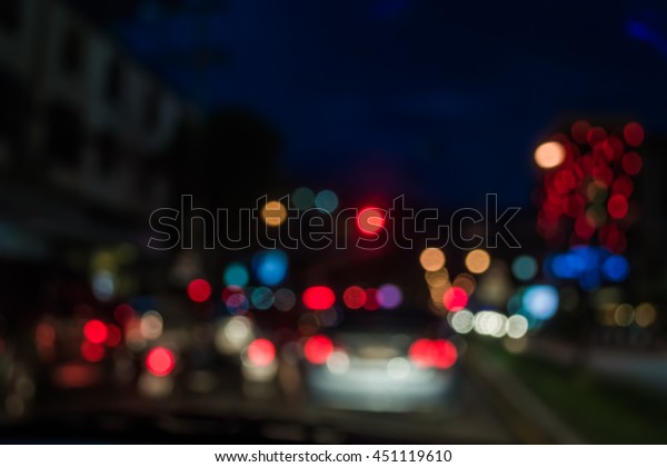 blur image of inside cars with\
bokeh lights with traffic jam on night time for background\
usage