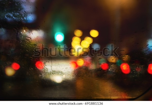 Blur image of raindrop on window with the rainy\
night city