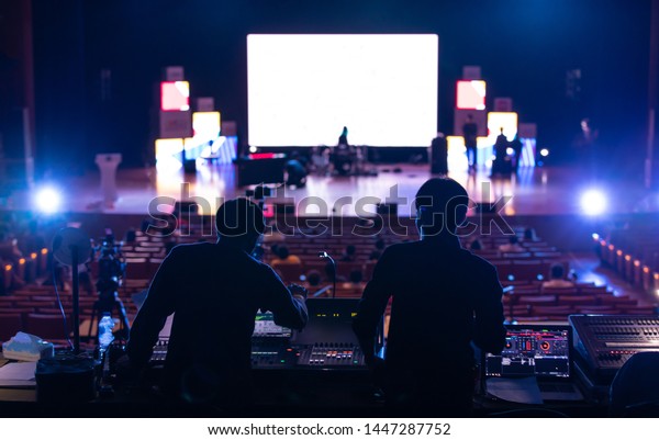 Blur image of sound\
engineer backstage crew team working to setting and preparing\
production for show events or music concert stage with blurry white\
screen in background.