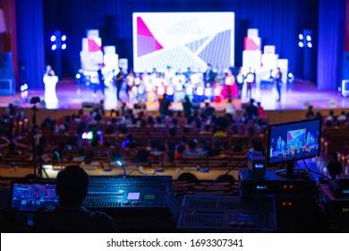 Blur Image Of Sound Engineer Team Working To Prepare For Music Concert Stage. Backstage Crew Event Team Control And Monitor Video Production Behind The Rows Of Audiences In The Live Show Hall.