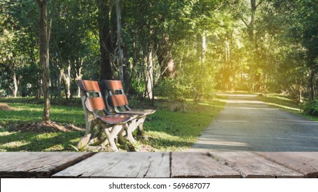 blur image of wood bench for resting and relaxing beside walkway in the park with selected focus empty wood table for display your product