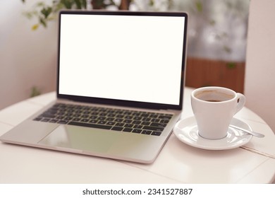 Blur laptop computer with blank white screen with coffee cup on white table background. Working business concept. - Powered by Shutterstock