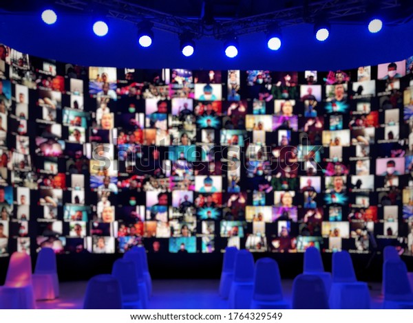 Blur\
large LED screen show many people\'s faces join big online event or\
virtual reality live conference. Video conference, Work from home,\
Social distancing, New normal event production.\
