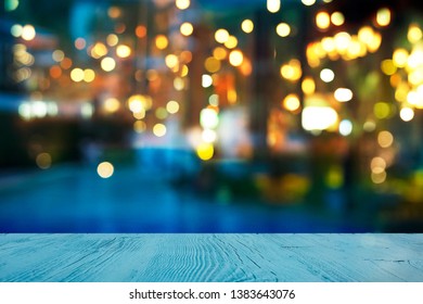 Blur Light Of Bar Or Pub Beside Blue Water Swimming Pool Summer Party At Night With Top Of Wood Table Background