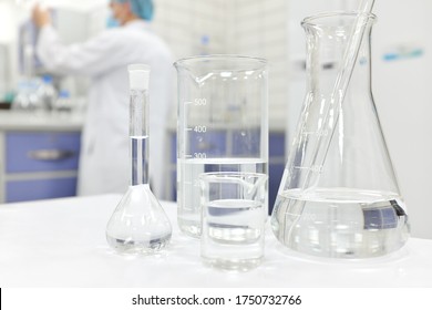 Blur Male Scientist Working In A Chemistry Science Laboratory  With Flask, Beaker And Glassware Containing Clear Liquid Chemical.