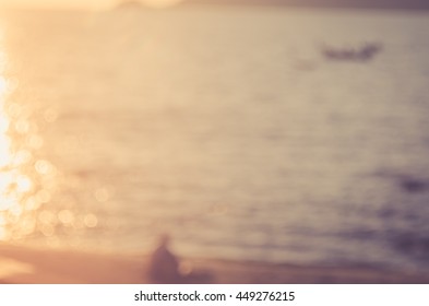 Blur Man Relax On Tropical Sunset Beach With Bokeh Sun Light Wave Abstract Background. Copy Space Of Summer Vacation And Business Travel Concept. Vintage Tone Color Style.