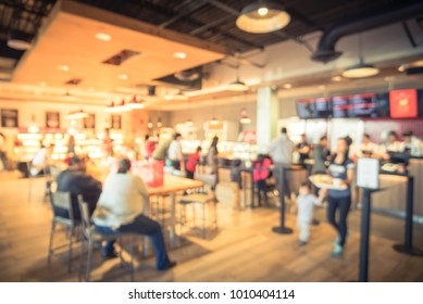 Blur modern hipster open coffee shop, self-serve bakeries in USA. Long people sit and stand queuing behind stanchion barriers check-out counter. Wall mount led menu board digital signage. Vintage tone - Shutterstock ID 1010404114
