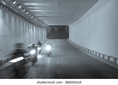 Blur motion group of people riding motorcycles thru a traffic tunnel in Hanoi in early morning. This is the most popular vehicle in Vietnam. Urban traffic concept. Transportation background. - Powered by Shutterstock