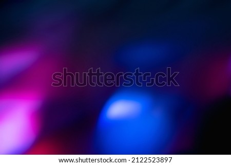 Blur neon light. Lens flare overlay. Bokeh fluorescent flash gleam. Defocused blue purple color flecks on dark black abstract background.