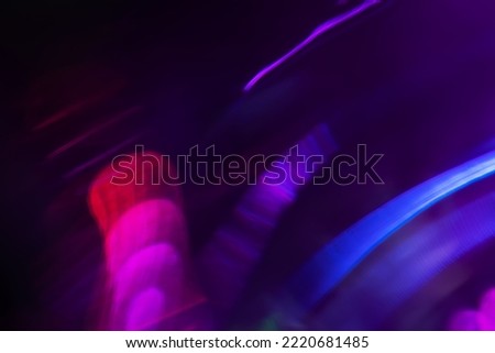 Blur neon light. Lens flare overlay. Bokeh fluorescent flash gleam. Defocused blue purple color flecks on dark black abstract background.