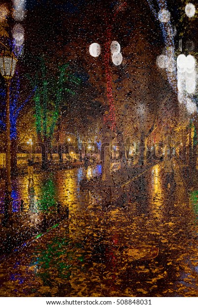 Blur night cityscape. The ancient center of\
the city at night after rain. Night urban street with bright\
colored lights of street cafes and moving cars. Motion blur, soft\
focus, stylization