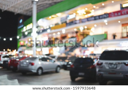 blur night light in business building with car park, abstract blurry bokeh of city background