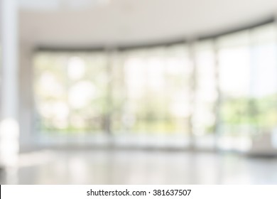 Blur office building, healthcare clinic, hospital or school background interior view looking out toward to empty lobby and entrance doors and glass curtain wall 