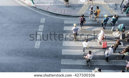 Blur people are moving across the pedestrian crosswalk in the city road (on top view)