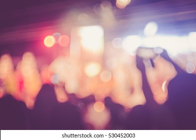 Blur People Taking Smart Phone In Night Outdoor Concert With Colorful Bokeh Abstract Background. Activity And Lifestyle Concept. Vintage Tone Filter Color Style.