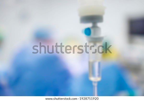 Blur photo for background.Intravenous fluid\
infusion during advance surgery inside operating room.Surgeon doing\
emergency surgery.Saline pump set drip to blood loss\
patient.Medical concept.