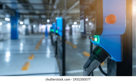 Blur Photo Of Electric Car Charging Station For Charge EV Battery. Plug For Vehicle With Electric Engine. EV Charger. Clean Energy. Charging Point At Car Parking Lot. Future Transport Technology.