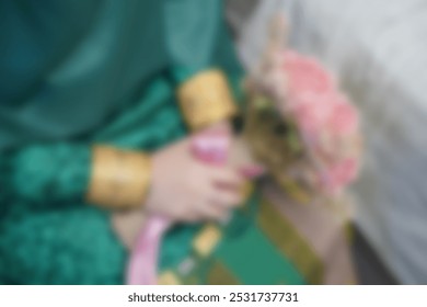 Blur photo Woman in a green indonesian kebaya or bugis attire with hands holding a beautiful artificial pink flower bouquet at the engagement event. Muslim engagement and wedding concept - Powered by Shutterstock