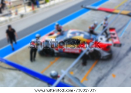 Blur professional pit crew ready for action as their team's race car arrives in the pit lane, concept of ultimate teamwork.