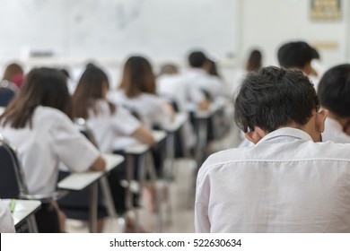 Blur School Or University Students Writing Answer Doing Exam In Classroom, View From Back Of The Class For Education Background 

