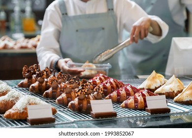 Blur seller wearing apron and putting delicious croissants on the store showcase of the bakery shop, Small business at home, Work from home. Selective focus. - Powered by Shutterstock