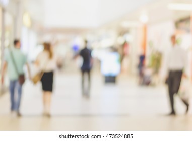 Blur Store With Bokeh Background. Silhouettes Of Business People In Blurred Motion Walking. Business People Walking In The Office Corridor.