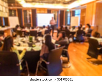 Blur Of Training Course In The Big Conference Meeting Room With Teacher Stand And Lecture To Student Sit In A Group At The Set Of Table And Chairs From Back Of The Luxury Meeting Room In The Hotel