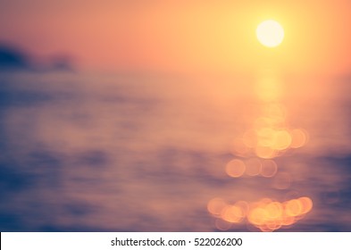Blur tropical sunset beach with bokeh sun light wave abstract background. Copy space of outdoor summer vacation and travel adventure concept. Vintage tone filter color style.