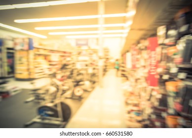 Blur Variety Of Fitness Equipment On Display At Sporting Goods Store In Houston, Texas, US. Defocused Pile Of Dumbbells, Weight, Strength Training, Stepper, Cardio Machine, Gym Room. Customer Shopping