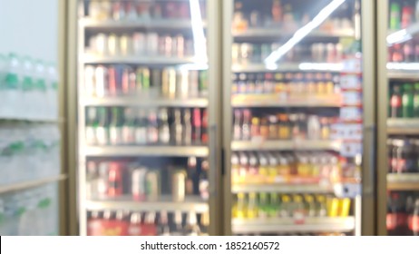 blur view of beverage displayed in refridgerators in convenience store with pure water bottle packs on the left. image of beverage cooler in market.