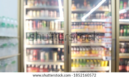 blur view of beverage displayed in refridgerators in convenience store with pure water bottle packs on the left. image of beverage cooler in market.