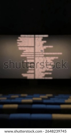 Blur view inside the cinema studio. Defocus of cinema seats and screen after the movie ends. Movie credits.