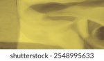 Blur of yellow fabric with subtle folds and a smooth, serene texture, capturing the essence of gentle warmth and softness, ideal for calm and cozy visuals