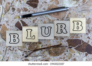 Blurb Concept With Reading Gasses And Fountain Pen On Marbled Stone Arranged Around The Word Formed Of Alphabet Letters On Wooden Cubes