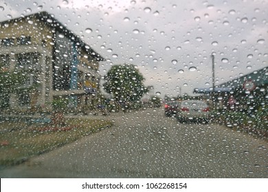 Blured background with rains drop on glass and cars on the road, Road view through car window blurry with heavy rain, Driving in rain, rainy weather. Water drop rain on road blur background. 