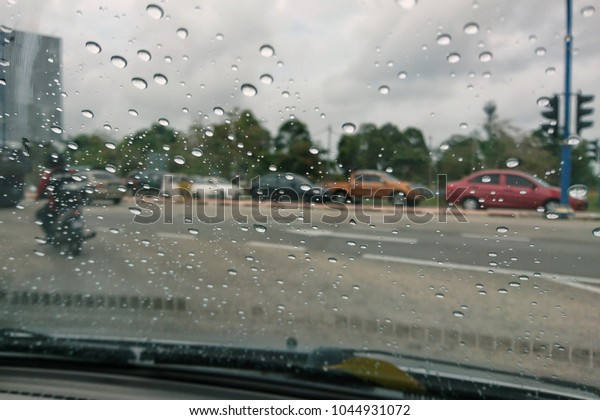 Blured background with rains drop on glass and\
cars on the road, Road view through car window blurry with heavy\
rain, Driving in rain, rainy weather.\
