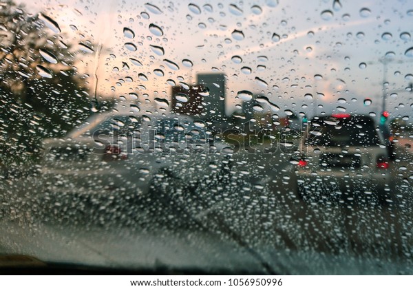 Blured\
background with rains drop on glass and cars on the road, Road view\
through car window blurry with heavy rain, Driving in rain, rainy\
weather. Water drop rain on road blur background.\
