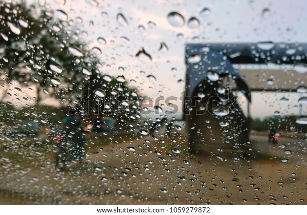 Blured\
background with rains drop on glass and cars on the road, Road view\
through car window blurry with heavy rain, Driving in rain, rainy\
weather. Water drop rain on road blur background.\
