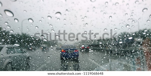 Blured background with rains drop on glass and\
cars on the road, Road view through car window blurry with heavy\
rain, Driving in rain, rainy\
weather