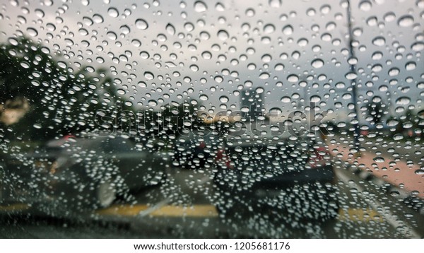 Blured background with rains drop on glass and\
cars on the road, Road view through car window blurry with heavy\
rain, Driving in rain, rainy\
weather.