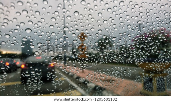 Blured background with rains drop on glass and\
cars on the road, Road view through car window blurry with heavy\
rain, Driving in rain, rainy\
weather.
