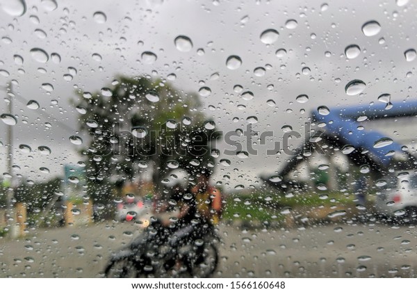 Blured\
background with rains drop on glass and cars on the road, Road view\
through car window blurry with heavy rain, Driving in rain, rainy\
weather. Water drop rain on road blur\
background.