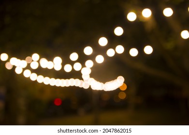 Blurred abstract background, backyard illumination, light in the evening garden, electric Defocused garland. Lamp garland of light bulbs on trees illuminate night scene - Shutterstock ID 2047862015