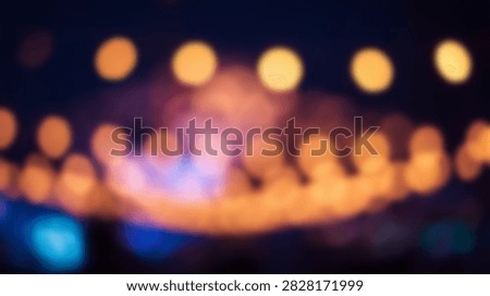 Blurred abstract background featuring a series of warm orange and cool blue bokeh lights creating a festive and magical atmosphere.